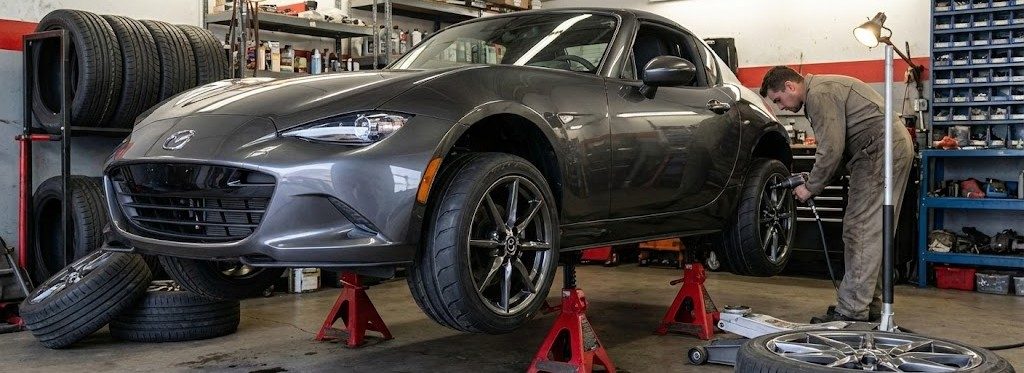 Mazda Miata on jack stands in a garage for tire service